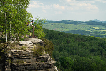 Adult male tourist with a backpack looking from a viepoint at sandstone rock formations in Tisá,...