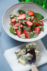 Plate of mangold, fresh strawberry and gorgonzola cheese salad, vertical shot on a grey concrete...