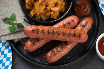 Close-up of bbq german bratwurst sausages with sauerkraut on a cast-iron tray, elevated view,...