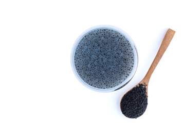 top view basil in glass of water with mucilage and raw seeds in wooden spoon isolated