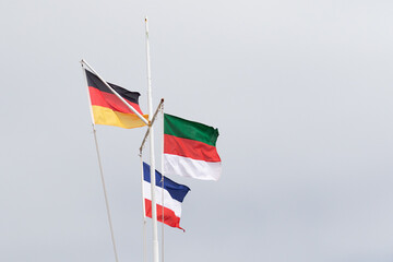 Flaggen von Deutschland, Helgoland und Jugoslawien vor bedecktem Himmel