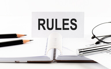RULES on paper card,pen, pencils, glasses,financial documentation on table - business concept