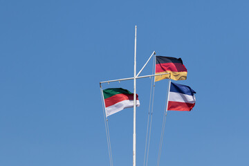 Flaggen von Deutschland, Helgoland und Jugoslawien vor blauem Himmel