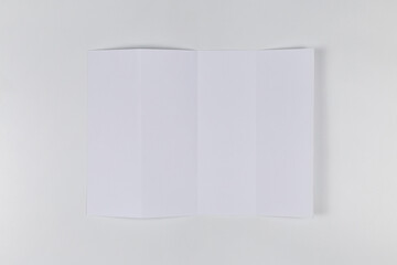 Empty sheet of paper folded four times on white background. Top view
