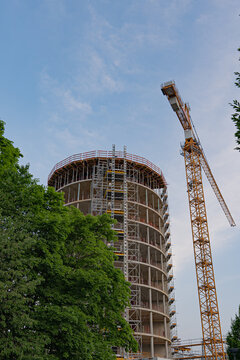 Construction site of a new round tower being build with a big crane - perspective from the street