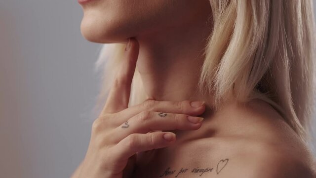 Skincare treatment. Cleansing moisturizing. Freshness beauty. Profile of confident blonde woman with nude makeup enjoying touching soft flawless radiant face neck bare shoulders skin.
