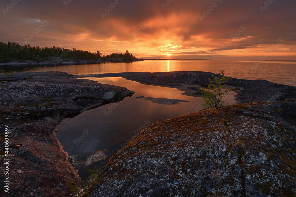 Wall mural puddles on the stone shore of the lake during the morning dawn