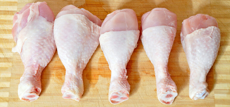 Fresh uncooked chicken meat drumsticks pieces and knife, baget ready to cook
