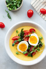 polenta bowl with eggs, fresh vegetables, microgreens. Mediterranean cuisine. vertical image. top view