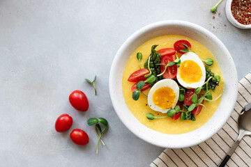 polenta or corn porridge served with fresh vegetables, microgreens and eggs. Healthy balanced lunch bowl. copy space