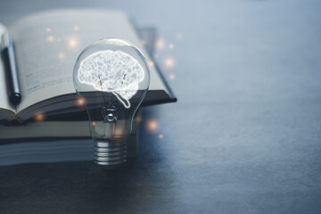 Bright light bulb with glowing brain and book or text book with copy space. Business and education idea concept of learning inspiration and knowledge cognition.