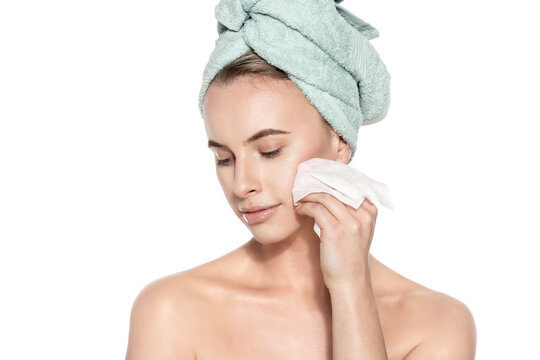 Attractive Young Woman With Her Hair Wrapped In A Towel, Removing Make Up. Pretty Girl With Perfect Complexion Cleansing Her Face Using Soft Face Wipe. Isolated On White Background.