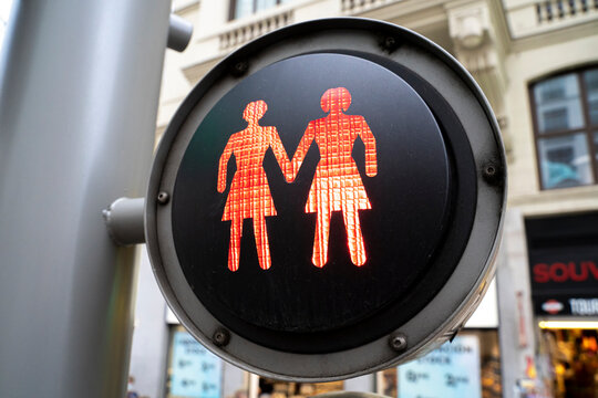 se&ntilde;ales de tr&aacute;fico para peatones de un sem&aacute;foro del centro de Madrid, simbolizando el orgullo gay y homosexual, con dos mujeres con falda cruzando de la mano, en rojo y en verde.