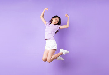 Young asian girl jumping up on purple background