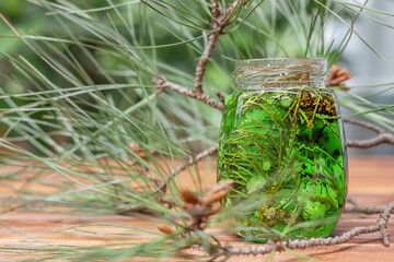 Pine jam. Glass jar with jam of young pine buds standing on a wooden countertop against the...