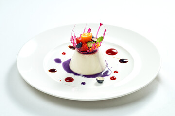 Delicious dessert - vanilla mousse with berry filling and caramel and berry decoration in a white...