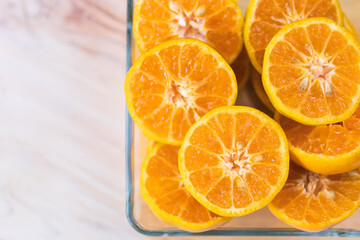 Fresh orange fruits in glass tray on wooden table. Top view with copy space.