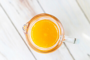 Jar of fresh orange juice on wooden table background. Top view.