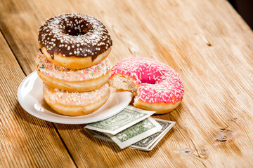 Donuts and money on wooden background