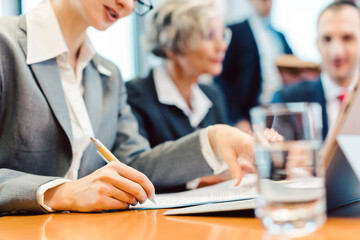 Close-up on woman taking notes during business meeting in office or board room