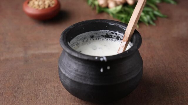 Pouring serving Spiced buttermilk , chaas , chaach , moru , sambharam , curd, lassi , yogurt, cool refreshing drink for hot summer in glass , Kerala, India Sri Lanka. Flavored Indian buttermilk.