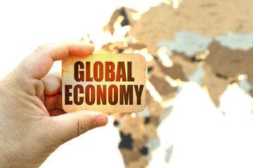 Against the background of the world map, a man holds a sign with the inscription - Global economy