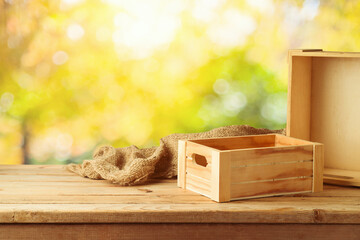 Empty wooden box on rustic table with sackcloth over fall bokeh background.  Autumn mock up for...
