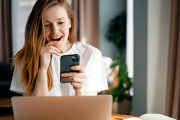 A young woman of European appearance in an apartment is playing with a gadget. Uses a mobile phone in his hands. Makes an online order with a credit card in an online store.