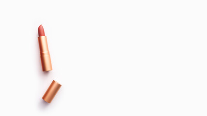 nude lipstick in a golden case on a light background, copy space