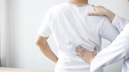 Physical therapy, Female physiotherapist treats back pain for a male patient attending a rehabilitation center, Bone arrangement, Non-surgical medical treatment, Modern medical techniques.