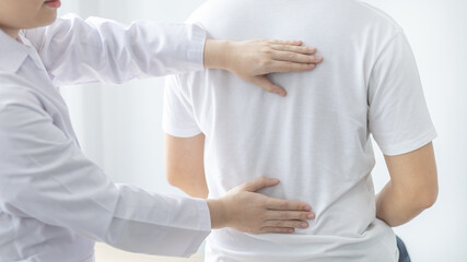 Physical therapy, Female physiotherapist treats back pain for a male patient attending a rehabilitation center, Bone arrangement, Non-surgical medical treatment, Modern medical techniques.