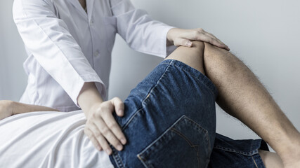Physical therapy, Female physiotherapist treats legs and hips pain for a male patient attending in...