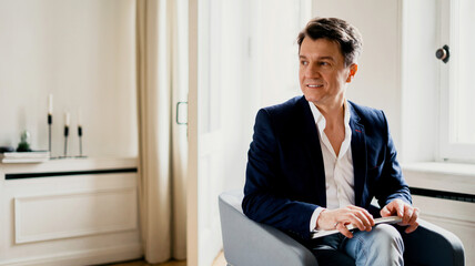 A male manager reads a book. An adult gray-haired man of European appearance is sitting in a...