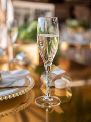 Close-up of a champagne glass in the gold decoration of a sumptuously decorated banquet table.
