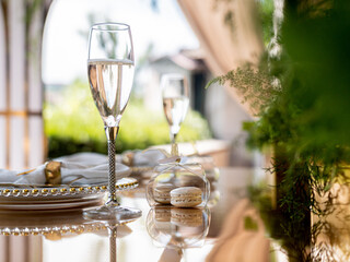 Exclusive decoration of the banquet table on the terrace in the luxury restaurant. A glass of expensive champagne on a gilded chair.