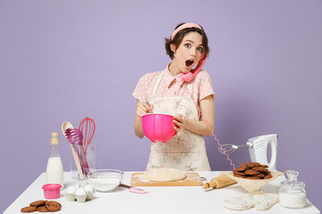 Young shocked housewife housekeeper cook chef baker woman in apron work at table kitchenware talk by handset phone whips whites look aside isolated on violet background Process cooking food concept.