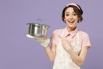 Young surprised happy housewife housekeeper chef cook baker woman in pink apron point index finger...
