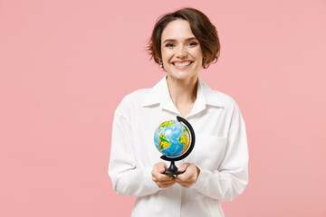 Fototapeta premium Happy fun smiling young employee business secretary woman 20s corporate lawyer in classic formal white shirt work in office hold in hands Earth world globe isolated on pastel pink background studio.