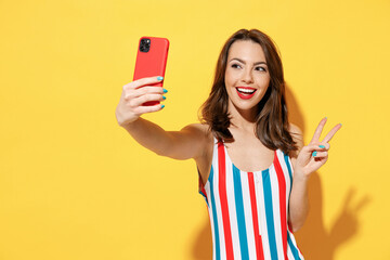 Happy young sexy woman slim body wear striped red blue swimsuit doing selfie hold mobile cell phone isolated on vivid yellow color wall background studio Summer hotel pool sea rest sun tan concept