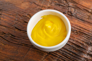 White gravy boats with cheese sauce on a wooden table.