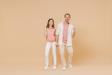 Full length happy overjoyed young parent man have fun with cute child teen girl in casual pastel clothes. Daddy little kid daughter do winner gesture clench fist isolated on beige color background