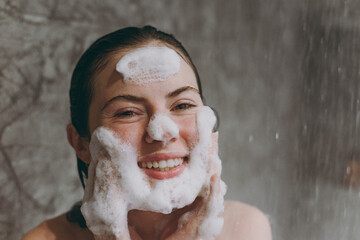 Close up cheerful half naked topless young wet haired woman 20s take shower wash face with...