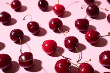 flat lay of messy cherries on a pink background