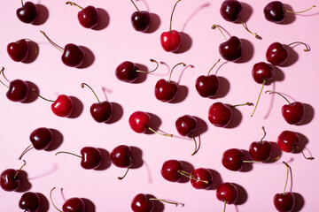flat lat of cherries on a pink background and hard shadows