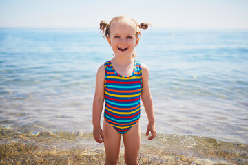 Happy little girl having fun on the beach at Mediterranean sea in France
