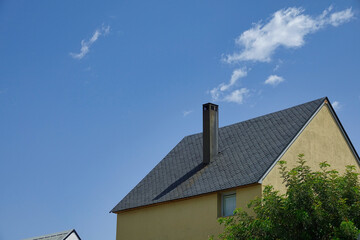 Tall chimney on roof with slate tiles