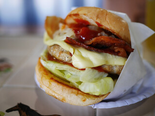 Local burger pork bacon with cheese in white papaer wrap