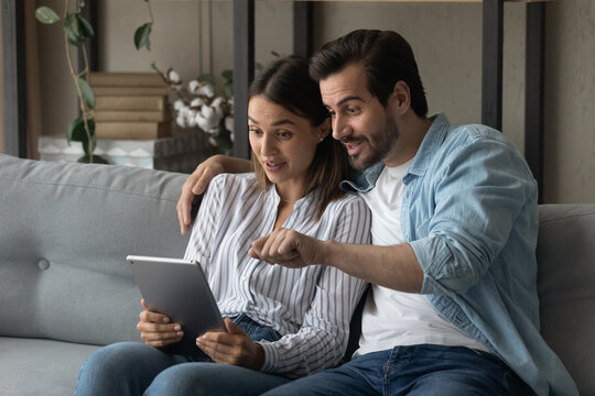 Surprised Young Happy Family Couple Looking At Digital Computer Tablet Screen, Feeling Excited Of Getting Email With Unbelievable News, Online Lottery Giveaway Win, Internet Success Concept.