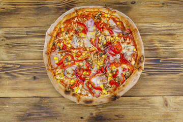 Delicious fresh pizza on a wooden table. Top view