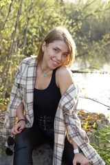Smiling girl with light brown hair and a checkered shirt, sunny warm day.
